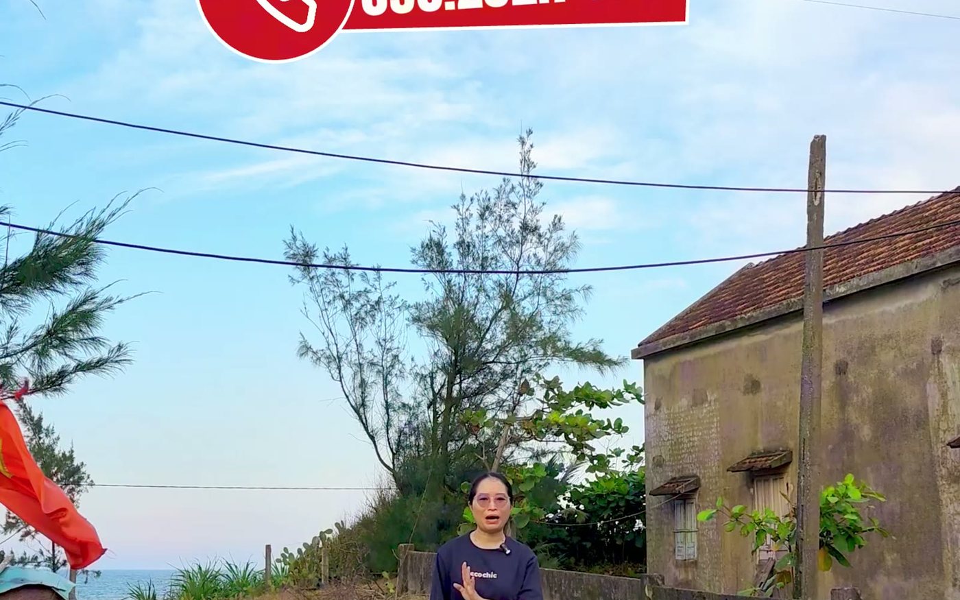 Lô đất có căn nhà cũ trên đó, phía trước là đường bê tông và hàng cây