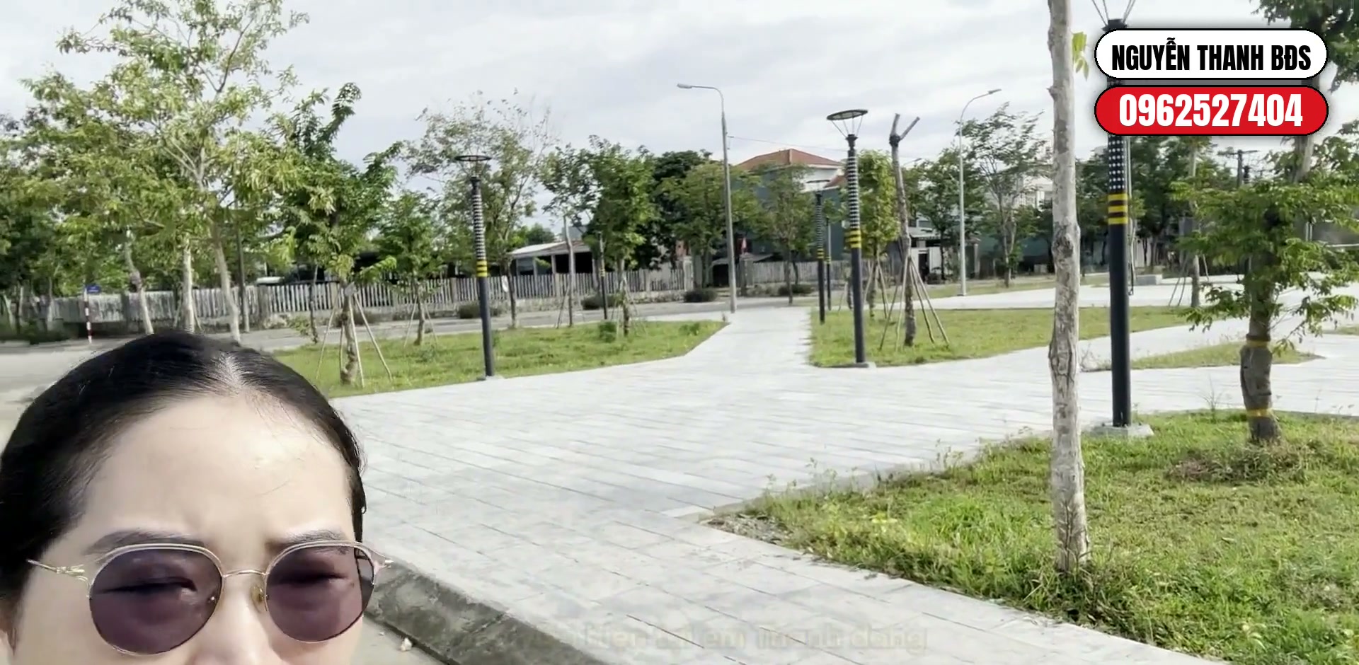 Nguyễn Thanh đứng bên đường Trần Thái Tông, phía sau là công viên với lối đi lát gạch và cây xanh mới trồng trong khu ADB Tam Kỳ