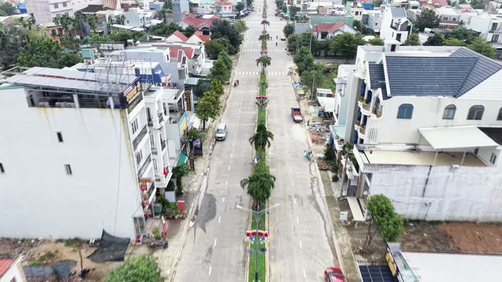 Trục đường lớn có dải phân cách trồng cây ở trung tâm Điện Bàn nhìn từ flycam, hai bên nhà dân và hàng quán đã kín