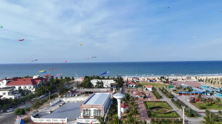 Bãi biển phía Nam Đà Nẵng nhìn từ trên cao, nhiều con diều bay trên quảng trường ven biển, bãi cát dài và dãy nhà thấp phía trong