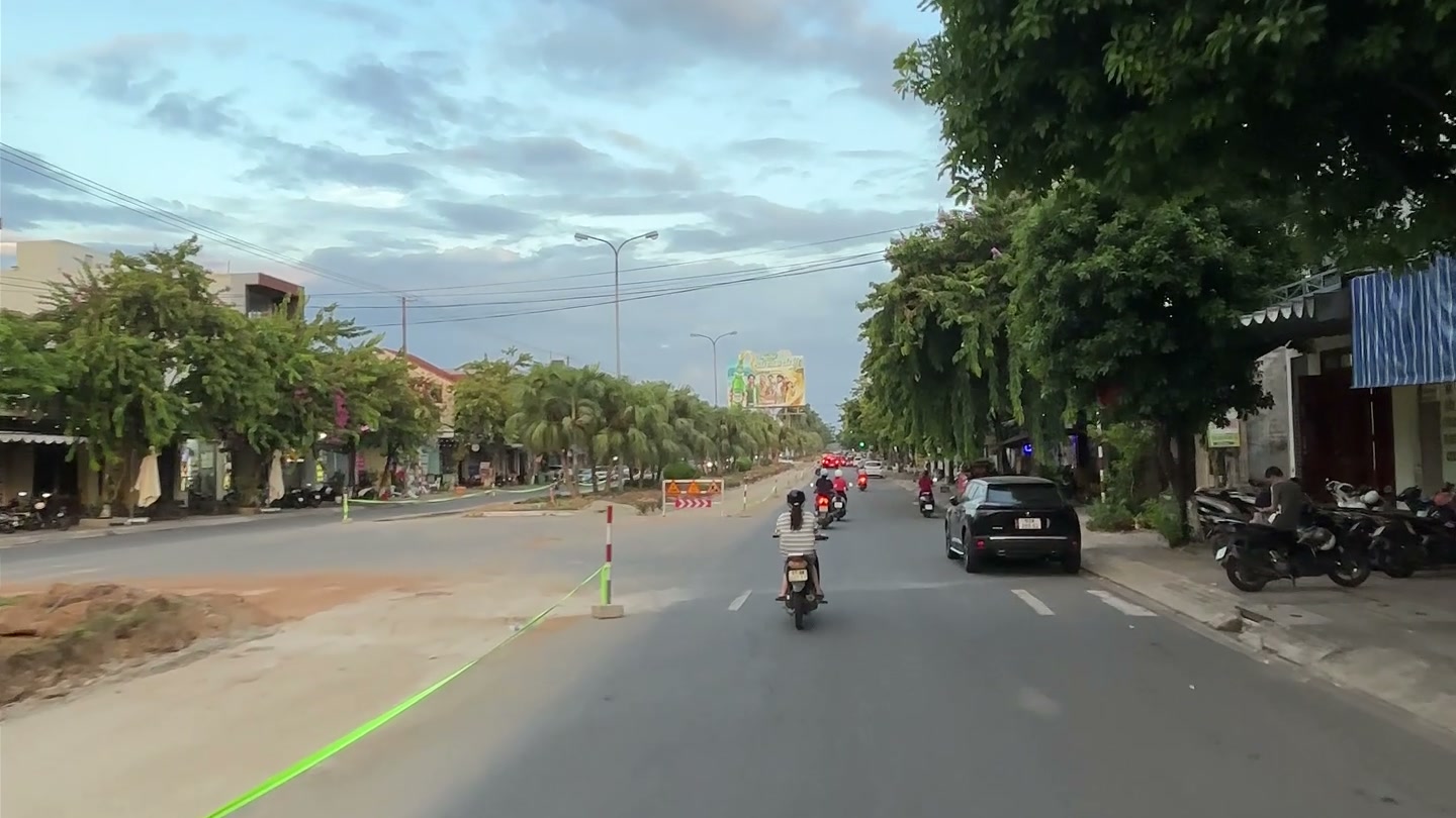 Mặt phố đường Hùng Vương Tam Kỳ, người dân chạy xe máy bên phần đường đang thi công, hai bên là nhà dân và hàng quán