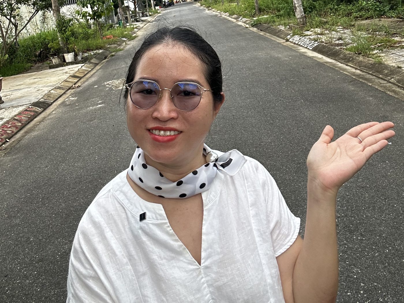 Nguyễn Thanh đứng trên đường Lê Văn Đức trong khu dân cư Trường Xuân Tam Kỳ, giơ tay chào