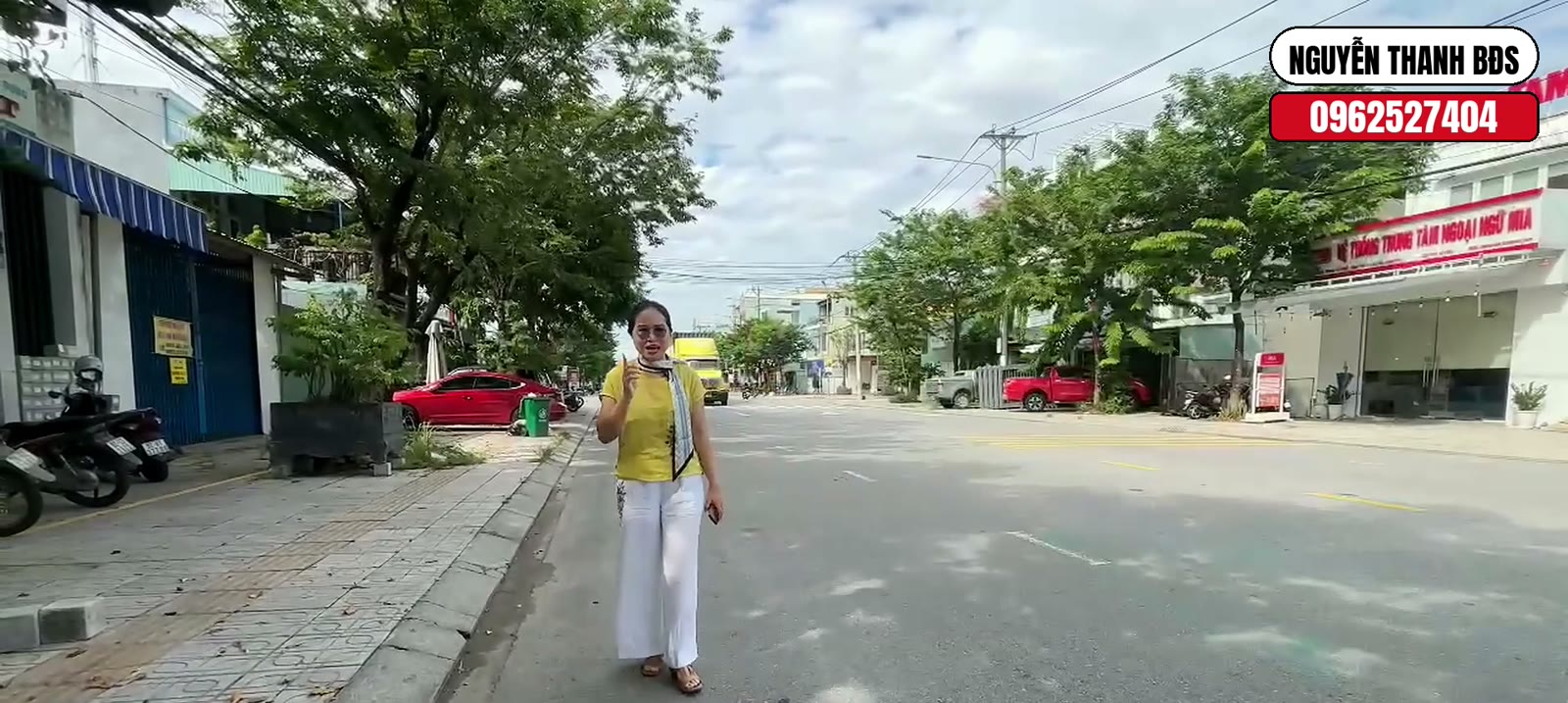 Đứng trên vỉa hè đường Nguyễn Văn Trỗi Tam Kỳ, xe tải và xe máy qua lại trên lòng đường rộng, hai bên là cửa hàng