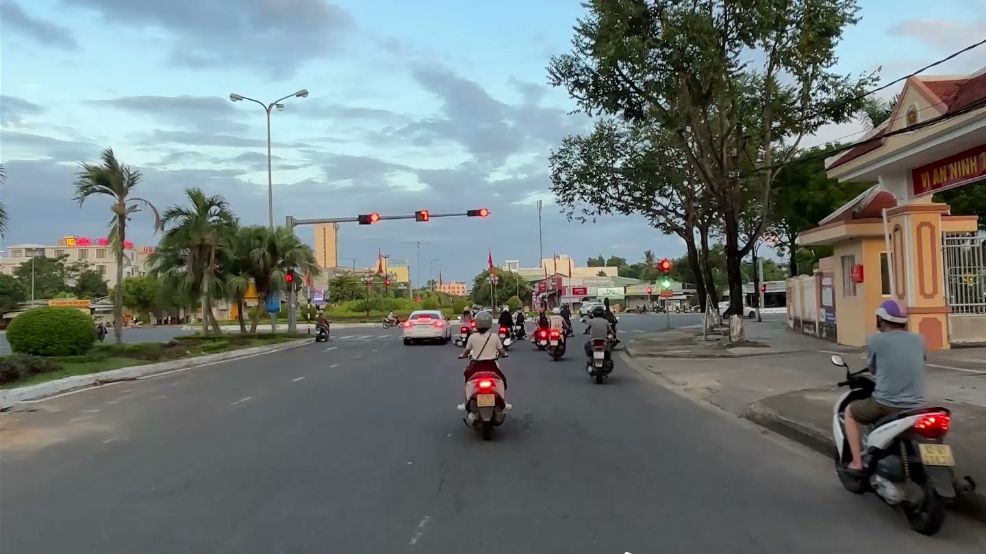 Đường Hùng Vương Tam Kỳ nhìn từ mặt đất, đèn tín hiệu và hàng cây hai bên, xe cộ qua lại buổi chiều