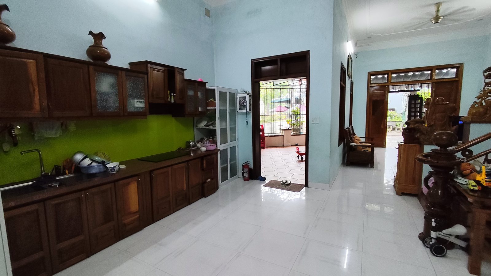 Bếp tủ gỗ kính ốp xanh lá có cửa riêng mở thẳng ra sân trong nhà 2 mặt tiền Tam Kỳ
