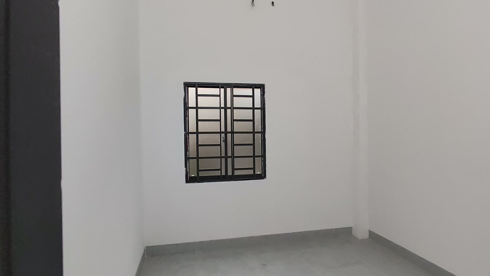 Cửa sổ khung sắt sơn đen ô vuông trên tường trắng phòng ngủ, ánh sáng tự nhiên chiếu vào, nhà kiệt Trần Cao Vân Tam Kỳ