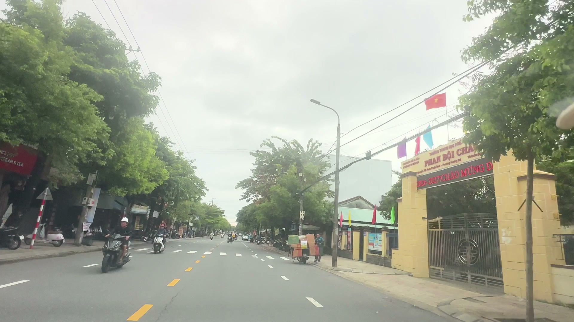 Đoạn đường Phan Châu Trinh ngang trường THPT Phan Bội Châu Tam Kỳ, cổng vàng bên phải, xe máy qua lại