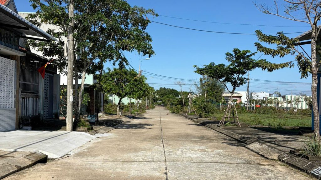 Đường bê tông trong khu dân cư 270 Quảng Phú, có cột đèn đường, cây xanh hai bên và nhà dân phía xa