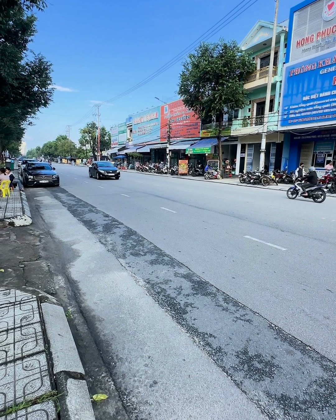 Đường Nguyễn Du Tam Kỳ nhìn từ vỉa hè, nhà phố và cửa hàng hai bên, xe máy đậu sát lề