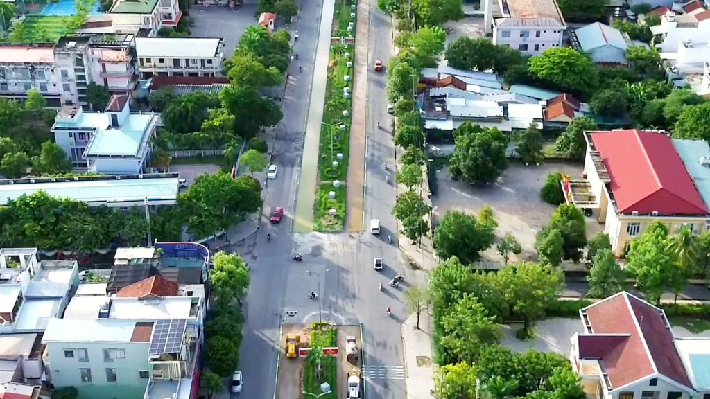 Dải phân cách rộng giữa đường Hùng Vương Tam Kỳ nhìn từ flycam, hai chiều xe chạy hai bên và máy công trình đang làm ở giữa