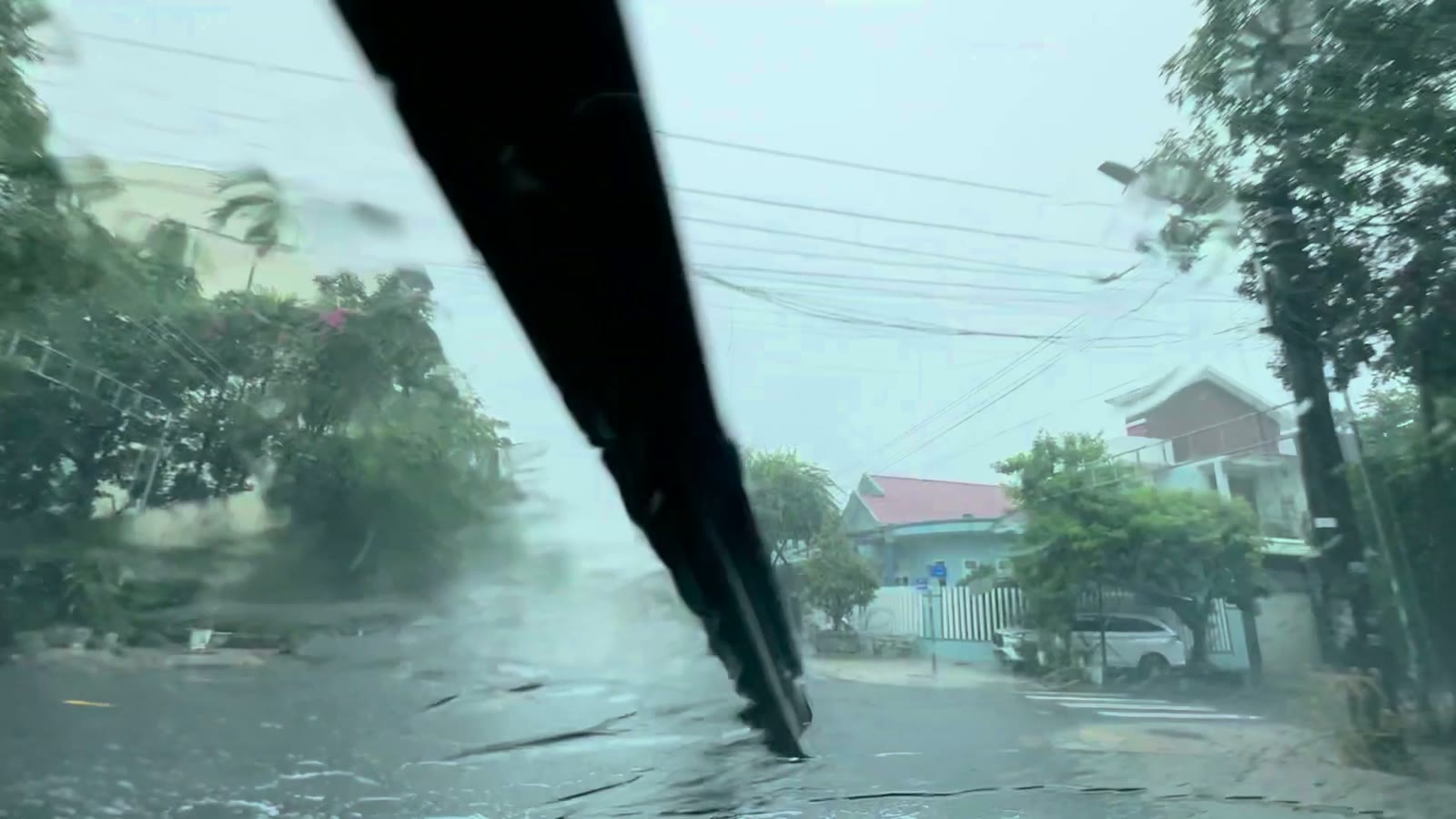 Đường trong khu dân cư bưu điện Tam Kỳ sáng mưa lớn 8/10/2026, mặt đường ướt, nhà và cây hai bên, không thấy nước đọng