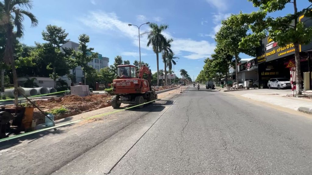 Máy xúc và ống cống bê tông xếp dọc dải phân cách cũ trên đường Hùng Vương Tam Kỳ, xe vẫn chạy trên phần đường cũ