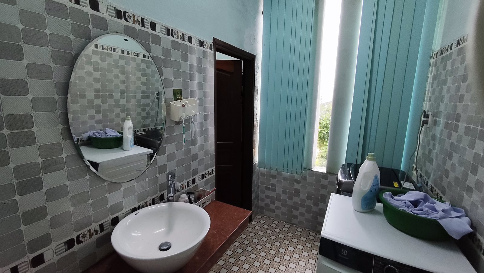 Nhà vệ sinh tầng 2 ốp gạch xám, gương tròn, lavabo sứ, có chỗ đặt máy giặt