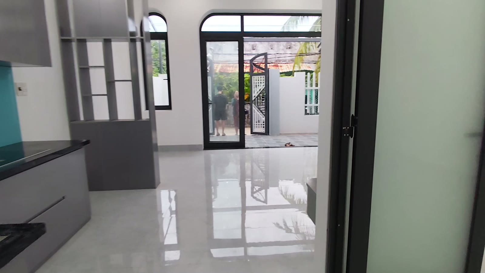 Nhìn từ trong nhà kiệt Trần Cao Vân ra cửa chính vòm kính, nền gạch sáng bóng, ngoài cửa là sân trước và cổng sắt