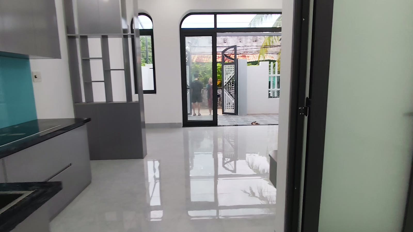 Từ góc bếp nhìn ra cửa chính vòm kính, nền gạch sáng bóng, sân trước và cổng phía ngoài, nhà kiệt Trần Cao Vân Tam Kỳ