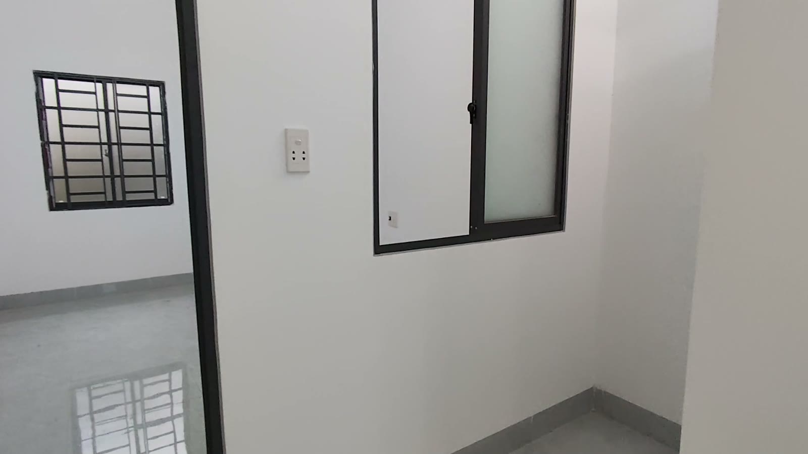 Phòng ngủ tường trắng có hai cửa sổ khung nhôm đen, nhà kiệt Trần Cao Vân Tam Kỳ