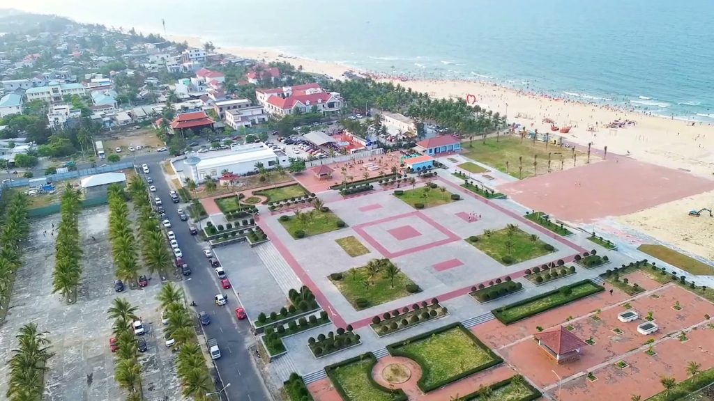 Quảng trường biển Tam Thanh nhìn từ flycam, sân lát gạch đỏ xen bồn cỏ, phía sau là bãi cát và biển