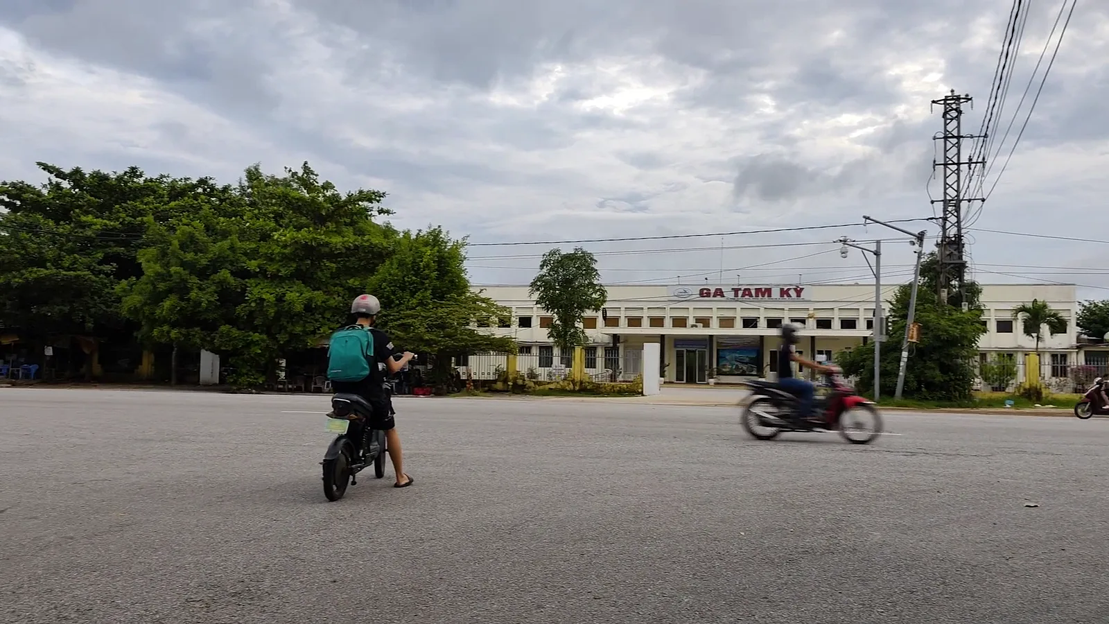 Nhà ga Tam Kỳ nhìn từ sân phía trước, bảng chữ Ga Tam Kỳ trên mái, vài người chạy xe máy ngang qua
