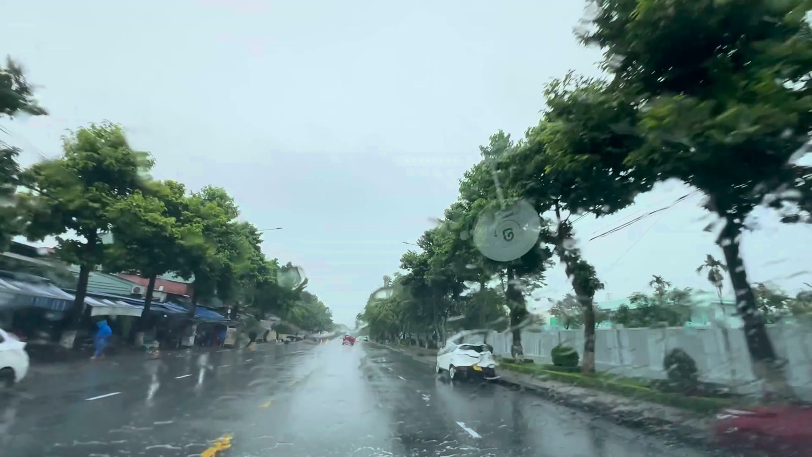 Trục đường đang nâng cấp ở Tam Kỳ với rào thi công và biển đi chậm ven đường trong sáng mưa lớn